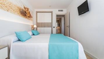 A hotel room with a bed, a TV, and a door leading to a bathroom.