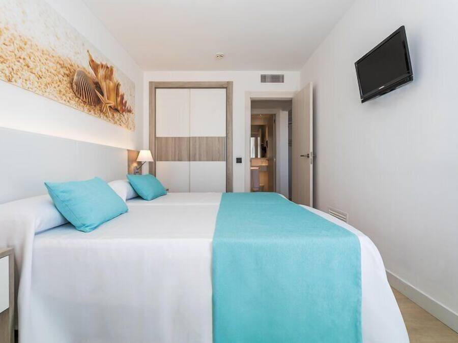 A hotel room with a bed, a TV, and a door leading to a bathroom.