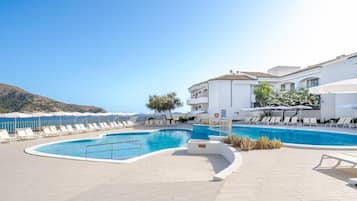 Una piscina techada, una piscina al aire libre, sombrillas
