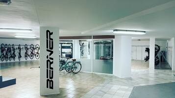 Un amplio espacio interior con piso de baldosas, un pilar grande con la palabra "BERNER" y varias bicicletas colgadas en la pared.