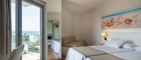 Ein Hotelzimmer mit großem Fenster, einer Couch, zwei Betten und einem Bild von Meeresschnecken.