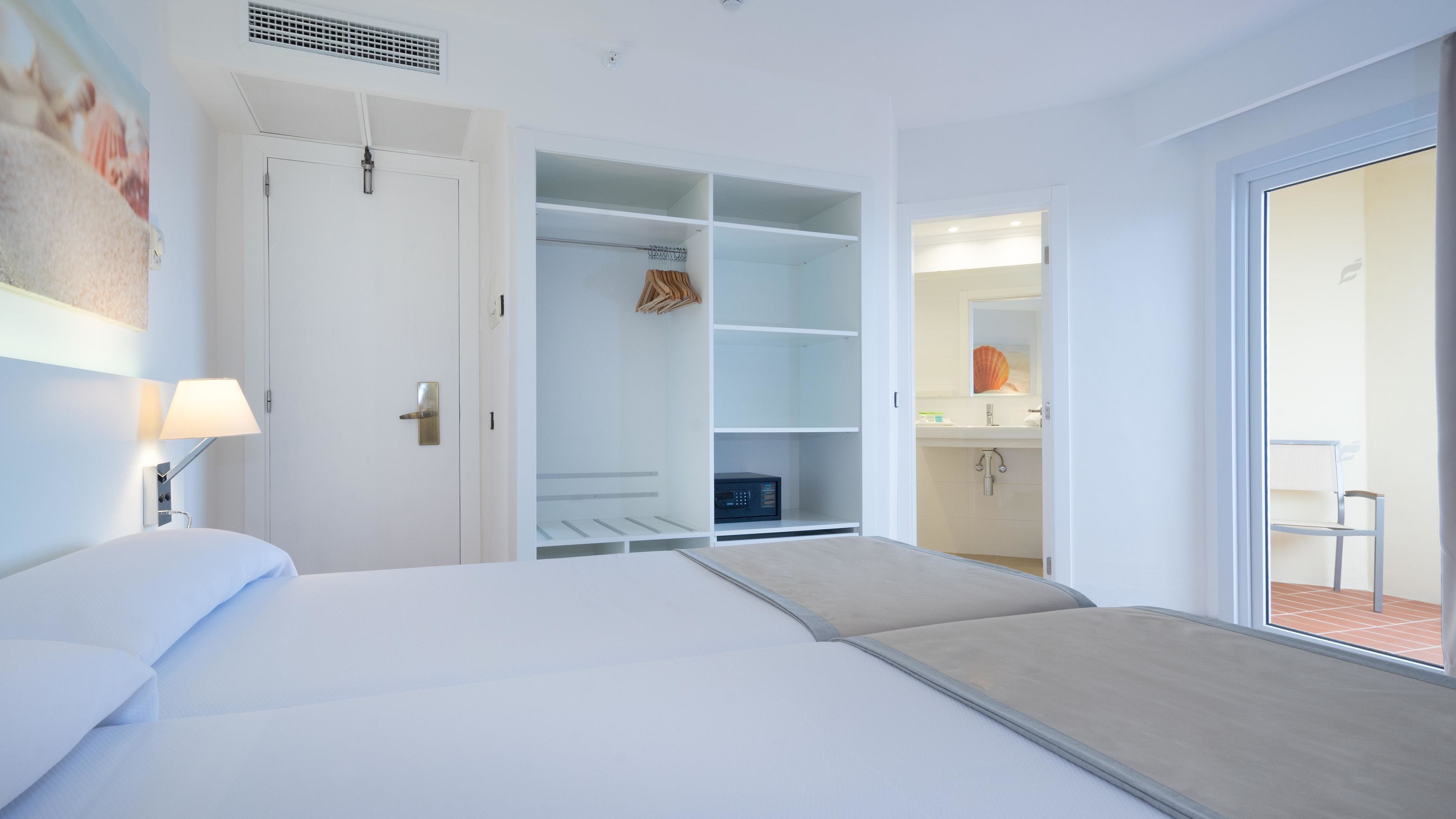 Habitación de hotel con cama, armario, baño y vista al exterior.