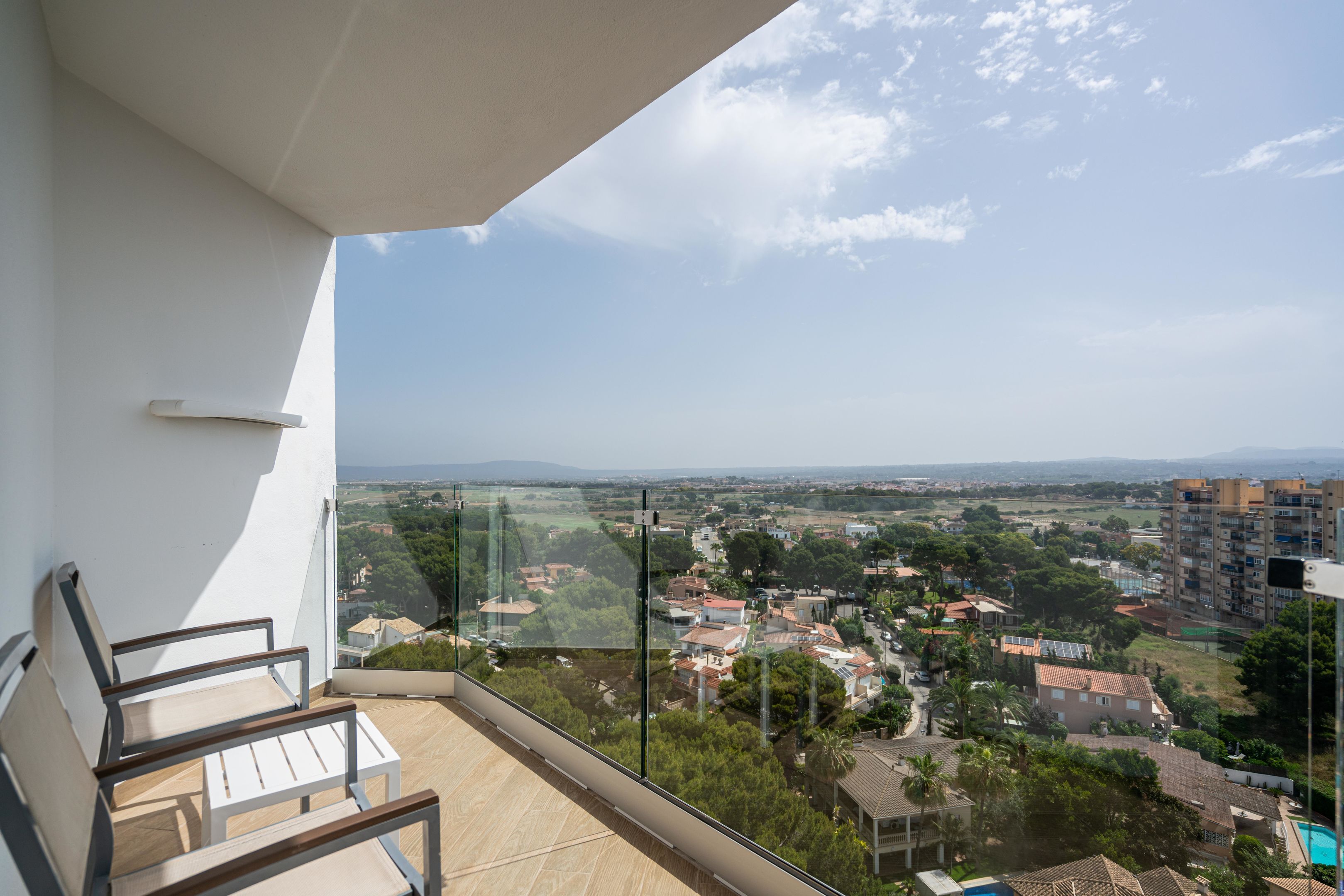 A balcony with a view of a residential area, including houses and a distant mountain range.