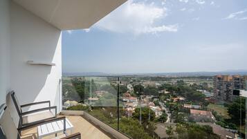 A balcony with a view of a residential area, including houses and a distant mountain range.