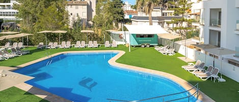 Una piscina con tumbonas y un carrito de aperitivos.