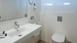 Une salle de bain moderne avec un lavabo blanc, un miroir et des toilettes.