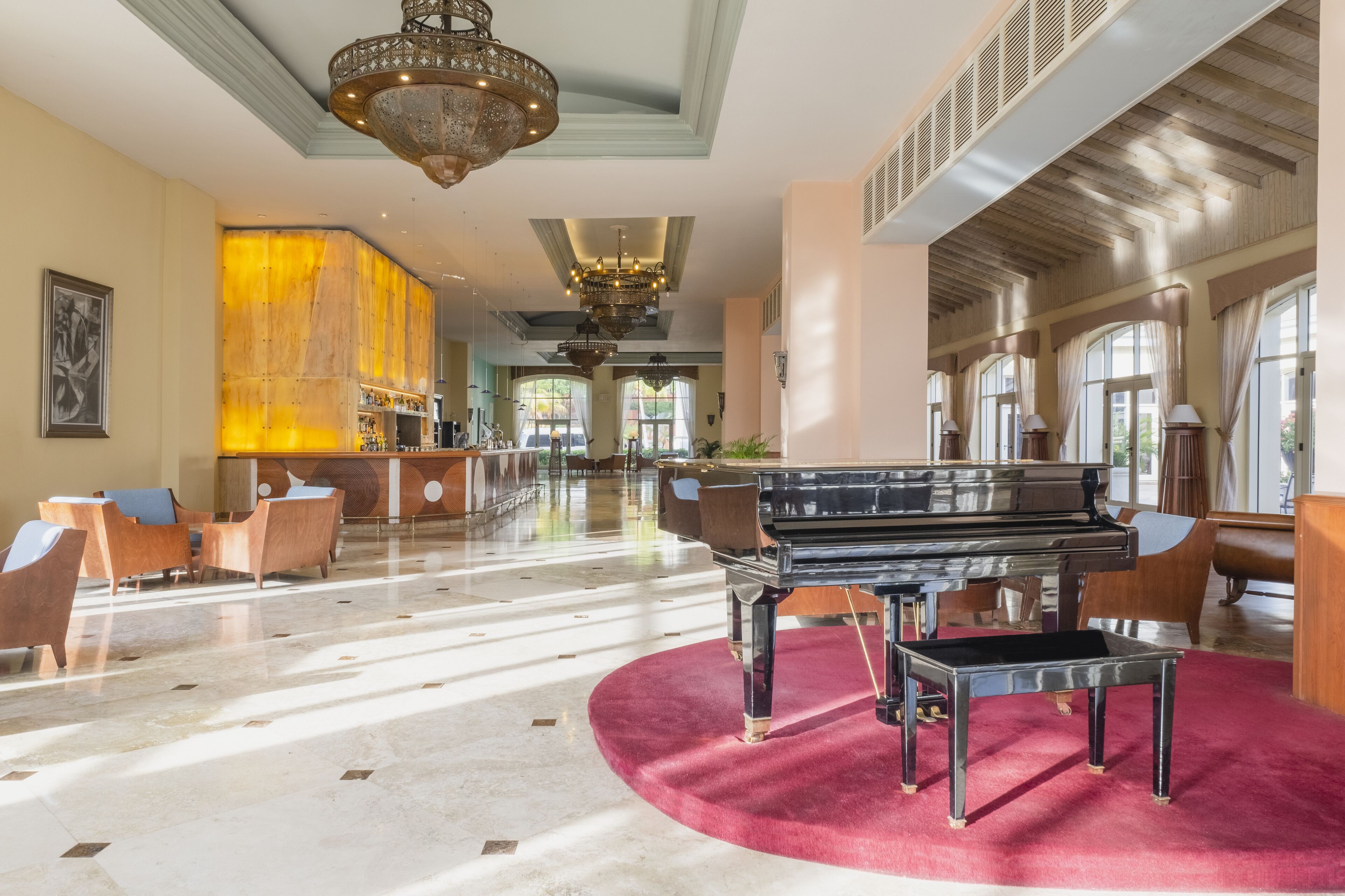 A grand lobby with a grand piano, marble flooring, and a chandelier.