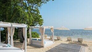 A beachside resort with wooden walkways, white canopied beds, and lounge chairs. - Iberostar Waves Rose Hall Beach - All Inclusive (Montego Bay)