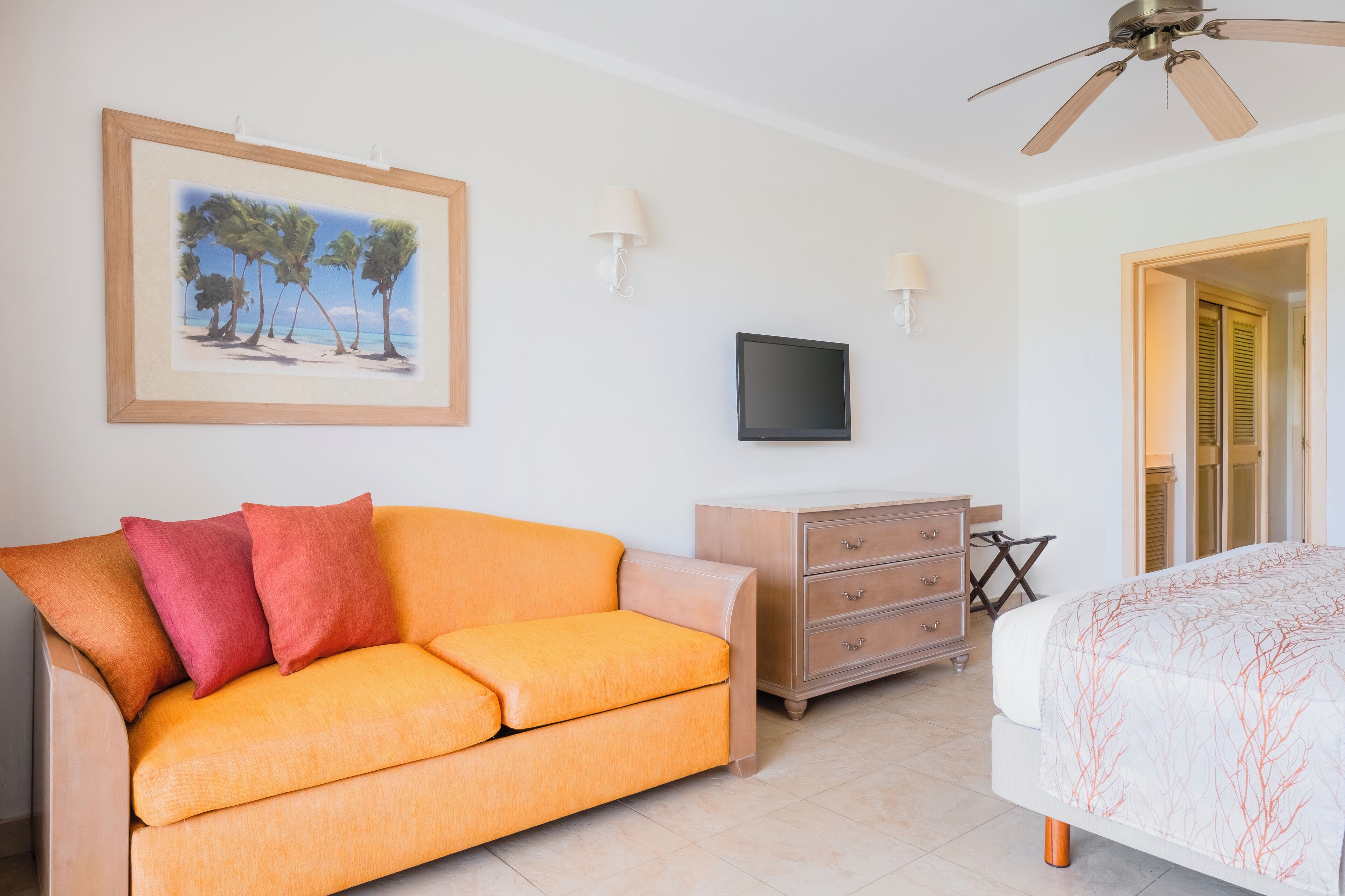 Una habitación de hotel con sofá, televisor, cómoda y cama.