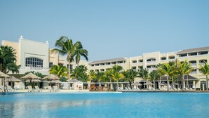 A resort with a swimming pool, palm trees, and a building with multiple balconies. - Iberostar Waves Rose Hall Beach - All Inclusive (Montego Bay)