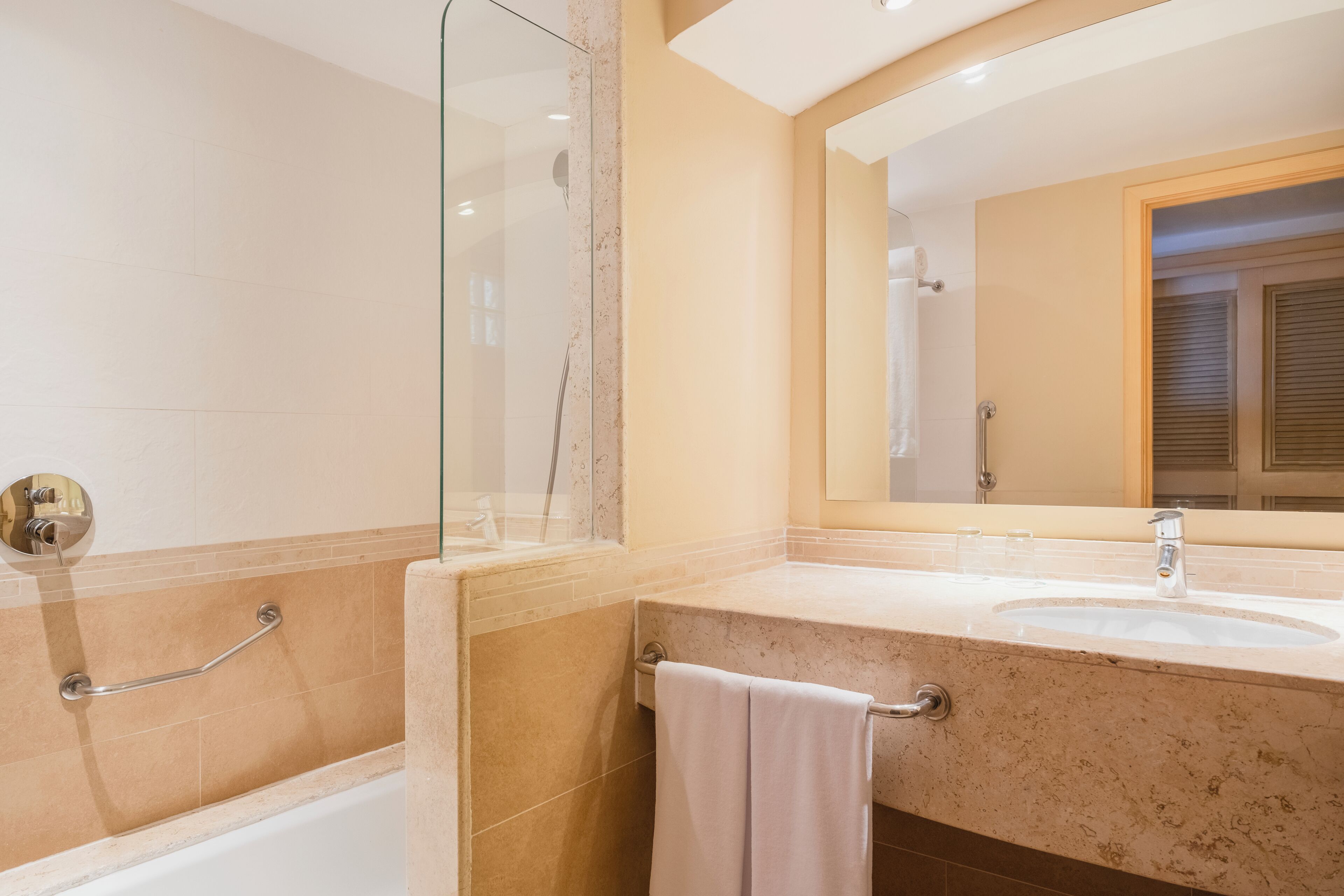 A bathroom with a bathtub, a sink, and a large mirror.