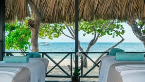 A beachside room with two beds, a thatched roof, and a view of the sea. - Iberostar Waves Rose Hall Beach - All Inclusive (Montego Bay)