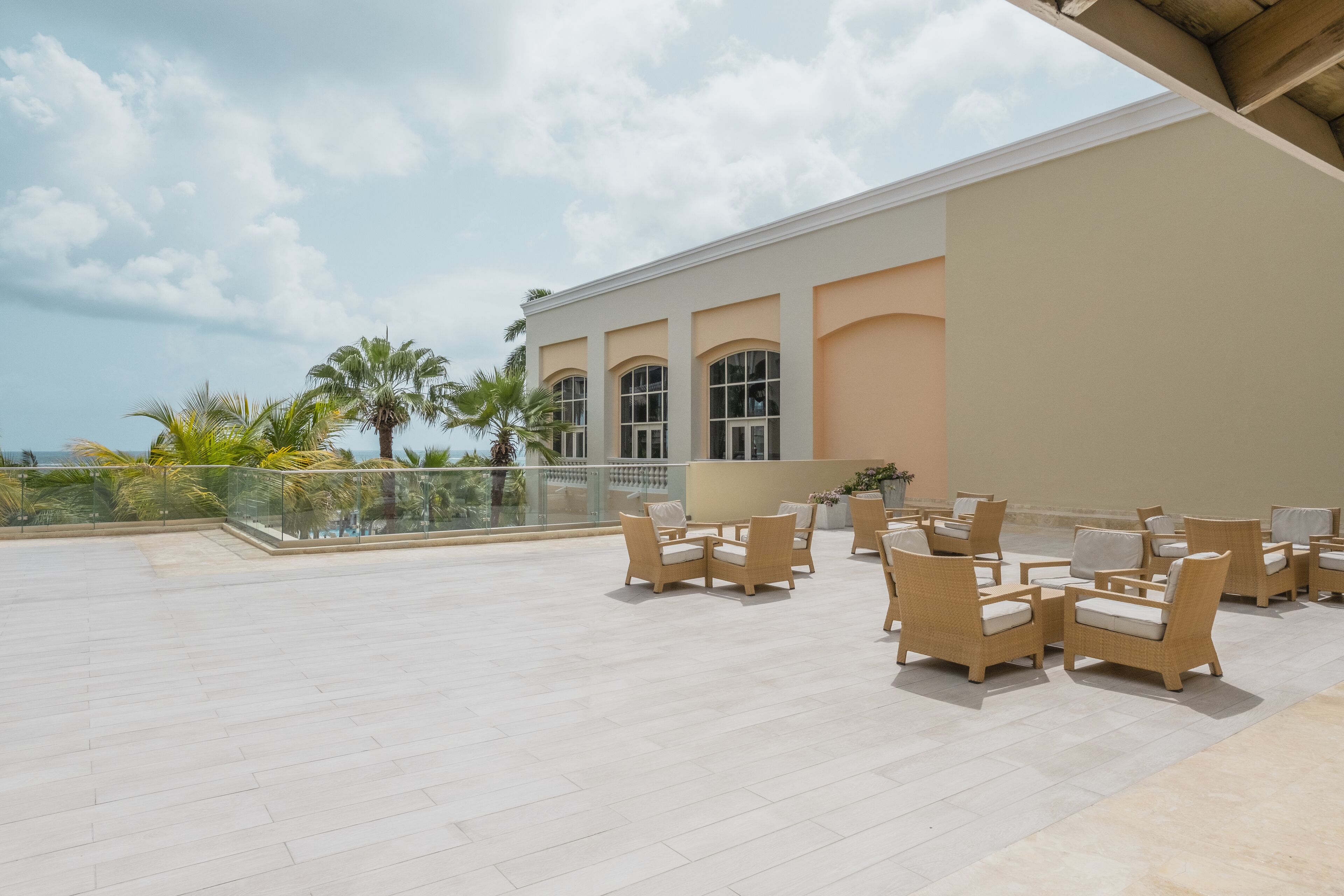 A spacious outdoor seating area with wicker furniture and a view of the ocean.