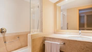 A bathroom with a bathtub, a sink, and a large mirror.