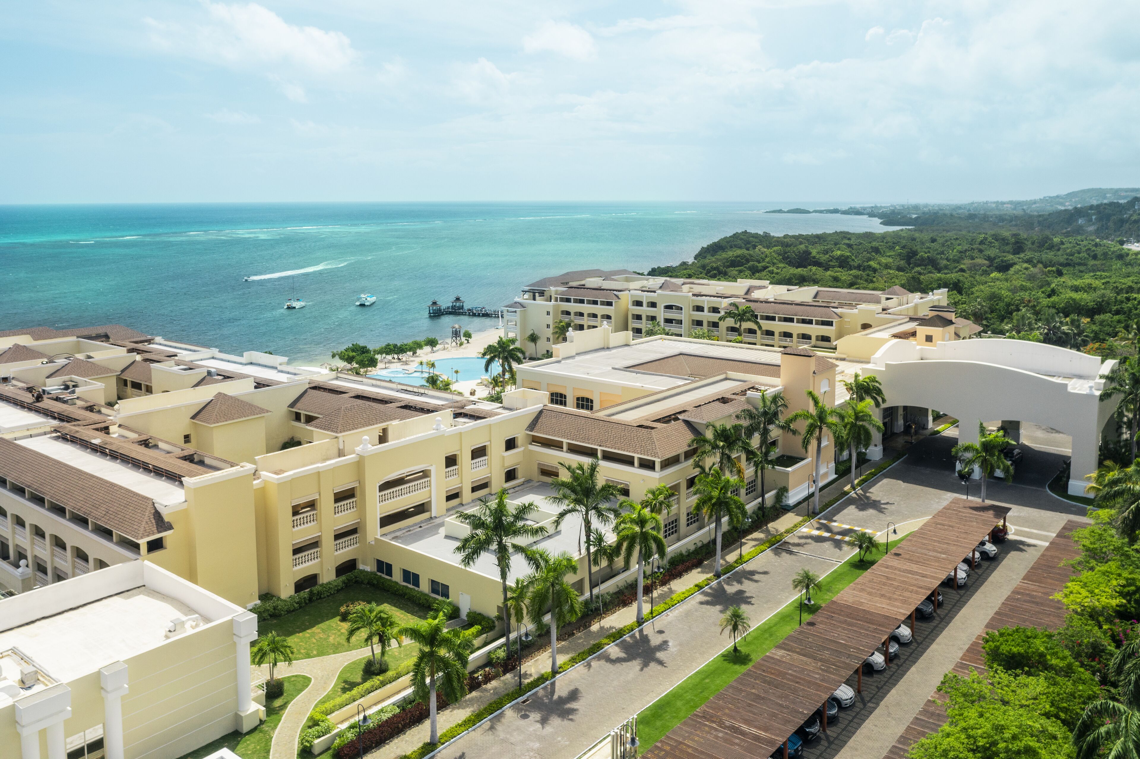 A resort with multiple buildings, a swimming pool, and a view of the ocean.
