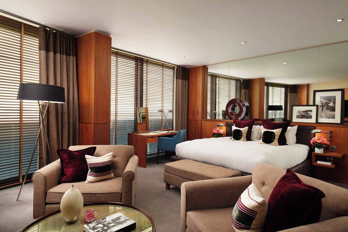 A hotel room with a large bed, two sofas, a desk, and a mirror.