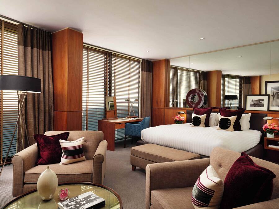Ein Hotelzimmer mit einem großen Bett, zwei Sofas, einem Schreibtisch und einem Spiegel.