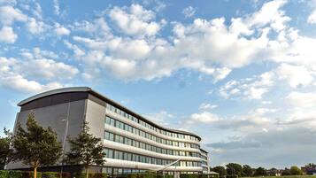 A modern building with a curved facade, large windows, and a well-maintained lawn.