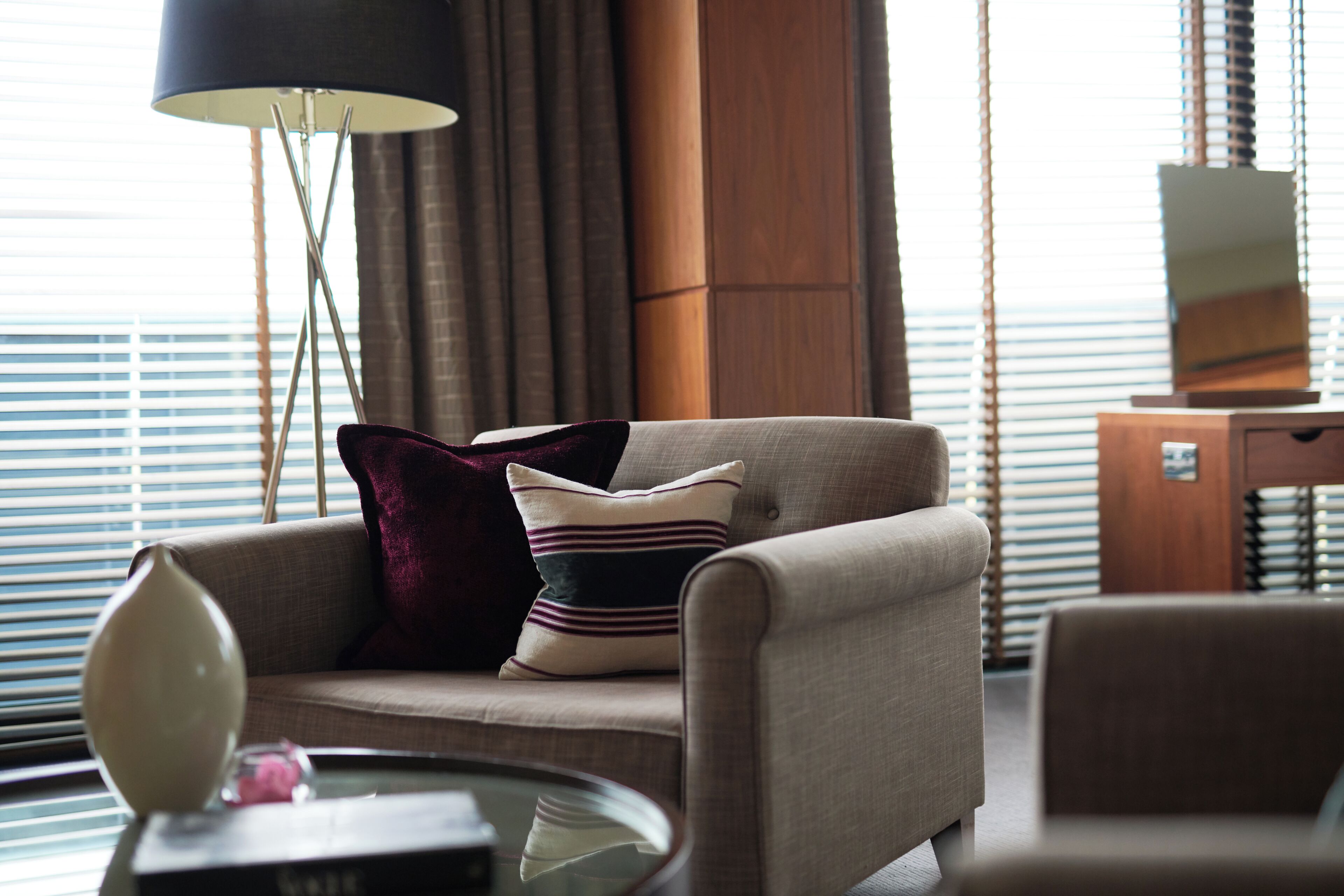 A modern living room with a sofa, a glass coffee table, and a lamp.
