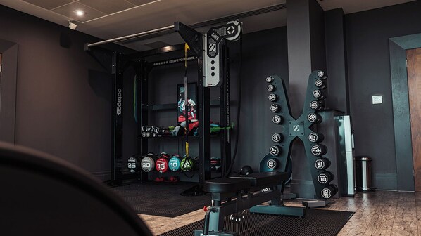 A gym with weightlifting equipment, including dumbbells and a squat rack.