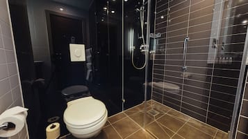 A modern bathroom with a glass-enclosed shower, a toilet, and a bidet.