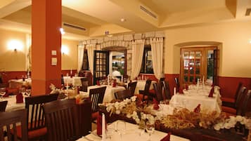 A restaurant with multiple tables set for dining, featuring white tablecloths and red napkins.