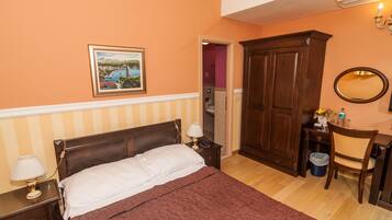 A bedroom with a bed, bedside table, lamp, wardrobe, and a mirror.