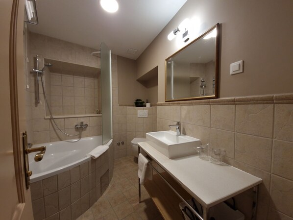 A modern bathroom with a bathtub, a shower, a sink, and a mirror.