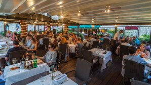 An outdoor restaurant with multiple tables and chairs, surrounded by greenery and a stone wall. - Villa Pattiera (Konavle)