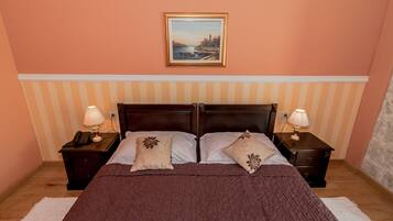 Quarto com uma cama de casal, duas mesas de cabeceira com abajures, um quadro na parede e um painel de parede listrado.