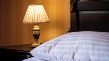 Cama com travesseiro branco e mesa de cabeceira com abajur.
