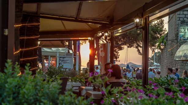 An outdoor dining area with tables and chairs, surrounded by greenery and flowers. - Villa Pattiera (Konavle)