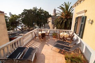 Una terraza con asientos al aire libre, una mesa y vistas a una iglesia y palmeras.