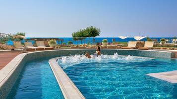 Una piscina al aire libre, sombrillas, sillones reclinables de piscina