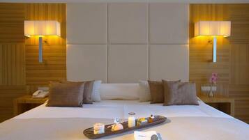 Quarto de hotel com uma cama grande, duas luminárias de cabeceira, mesa de cabeceira com telefone e bandeja com comida e chave.