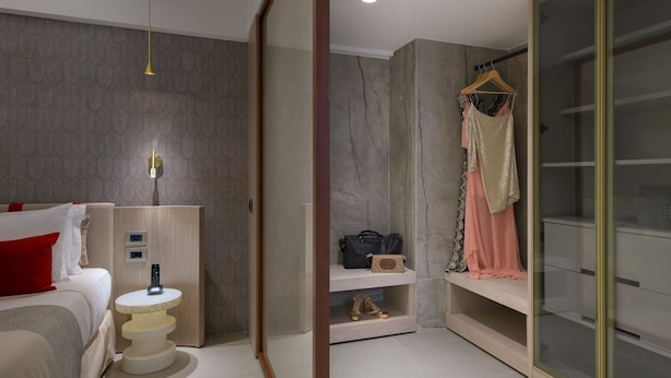 A modern hotel room with a bed, bedside table, and a vanity area with a mirror and shelves. - Elysium Resort & Spa (Rhodes)
