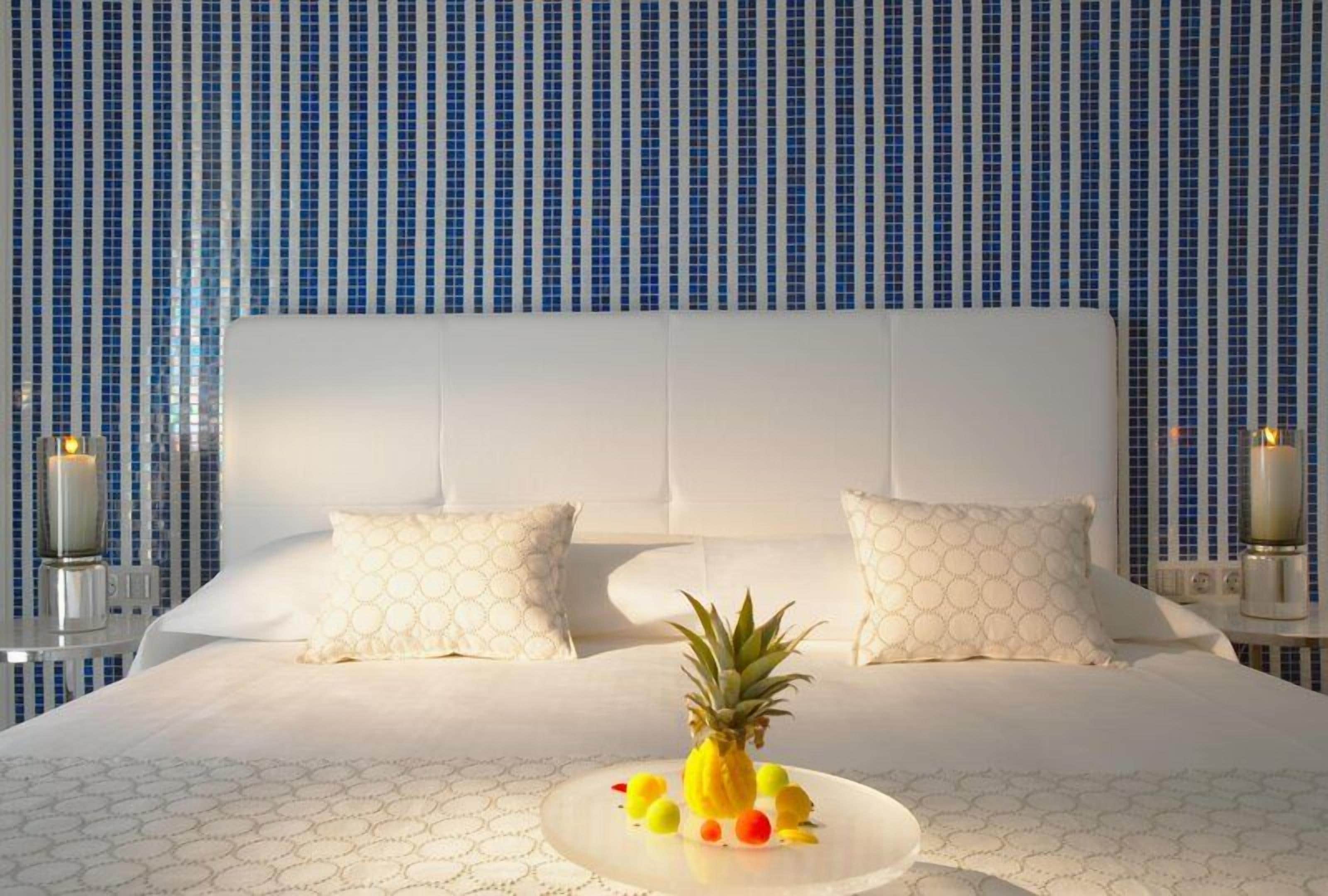 Una habitación de hotel con una cama grande, ropa de cama blanca y una piña sobre la cama.