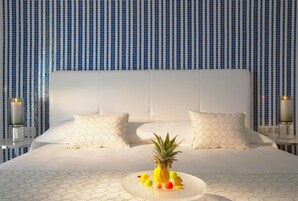 Una habitación de hotel con una cama grande, ropa de cama blanca y una piña sobre la cama.