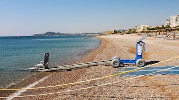 A beach with a jet ski, a lifeguard stand, and a row of beach chairs.