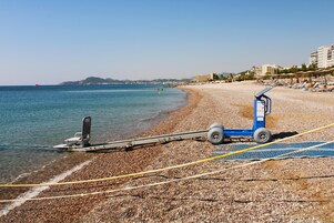Una playa con un jet ski, un puesto de salvavidas y una fila de sillas.