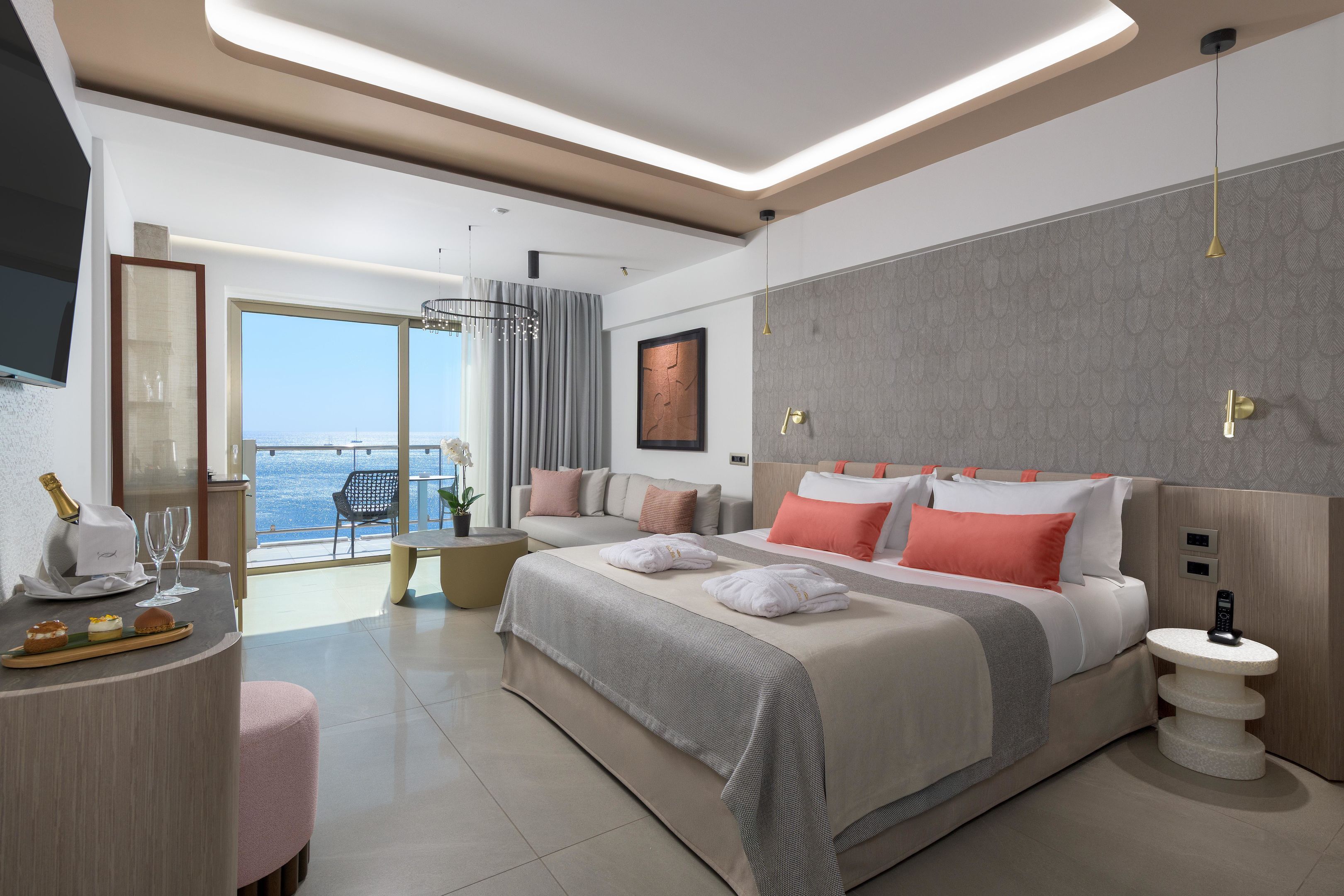 Una habitación de hotel moderna con una cama grande, una zona de estar con vistas y un balcón.