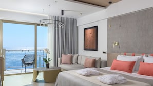 A modern hotel room with a large bed, a seating area with a view of the sea, and a dining table. - Elysium Resort & Spa (Rhodes)