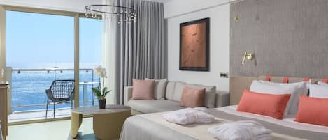 Una habitación de hotel moderna con una cama grande, un área de descanso con vista al mar y una mesa de comedor.