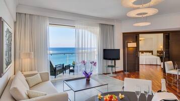Una camera d'hotel moderna con balcone, TV a schermo piatto, zona pranzo e un letto.