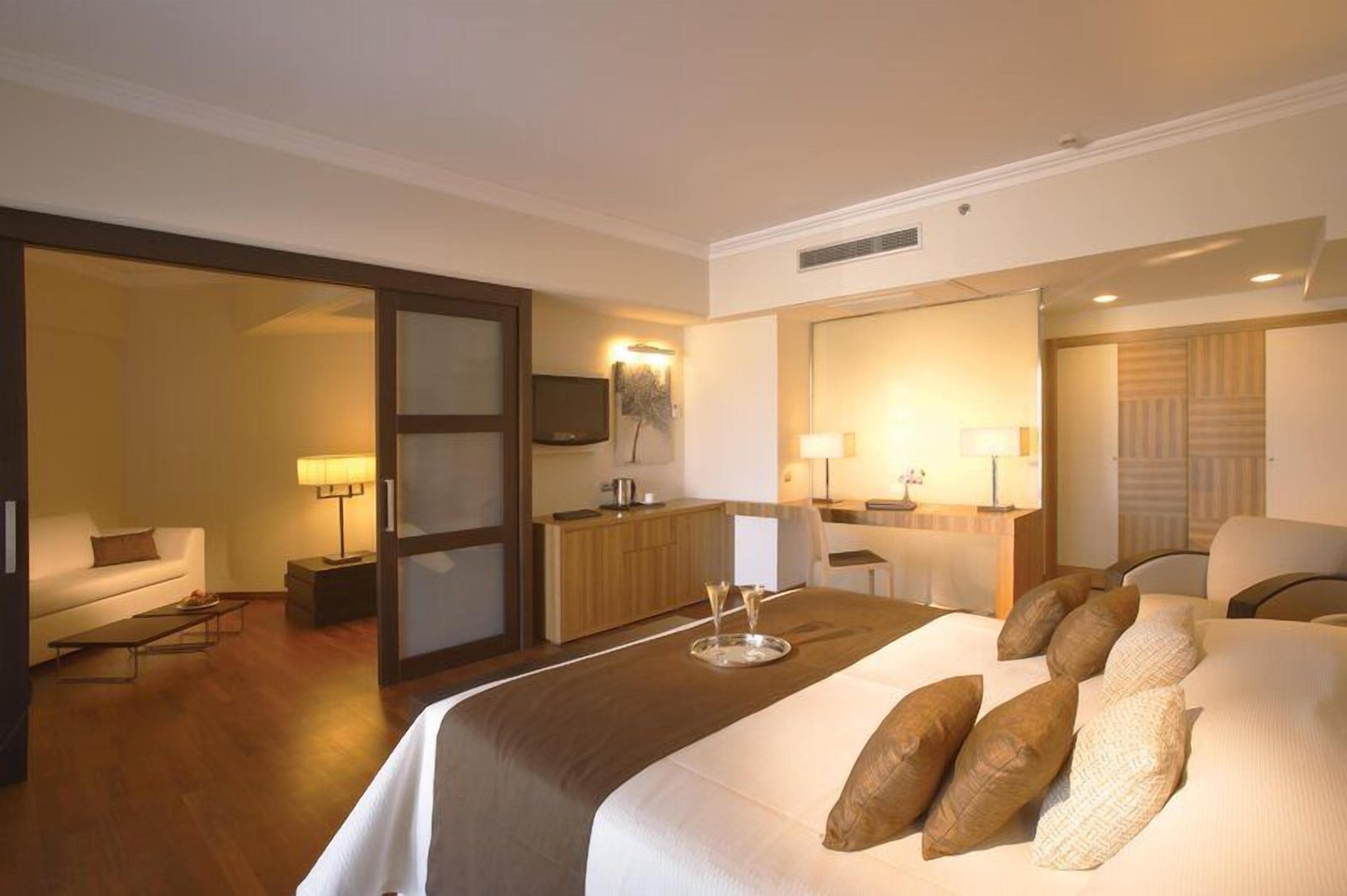 A hotel room with a bed, a desk, a chair, a sofa, and a television.