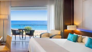 Una habitación de hotel con cama, una mesa, sillas y vista al océano.