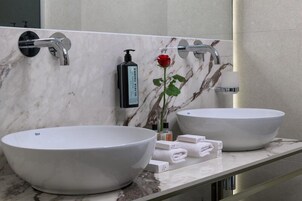 A bathroom with two large vessel sinks, a mirror, and toiletries on the counter.