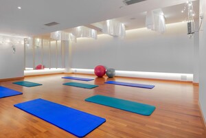 A spacious room with wooden flooring, exercise mats, and exercise balls.