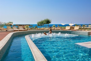Una piscina al aire libre, sombrillas, tumbonas