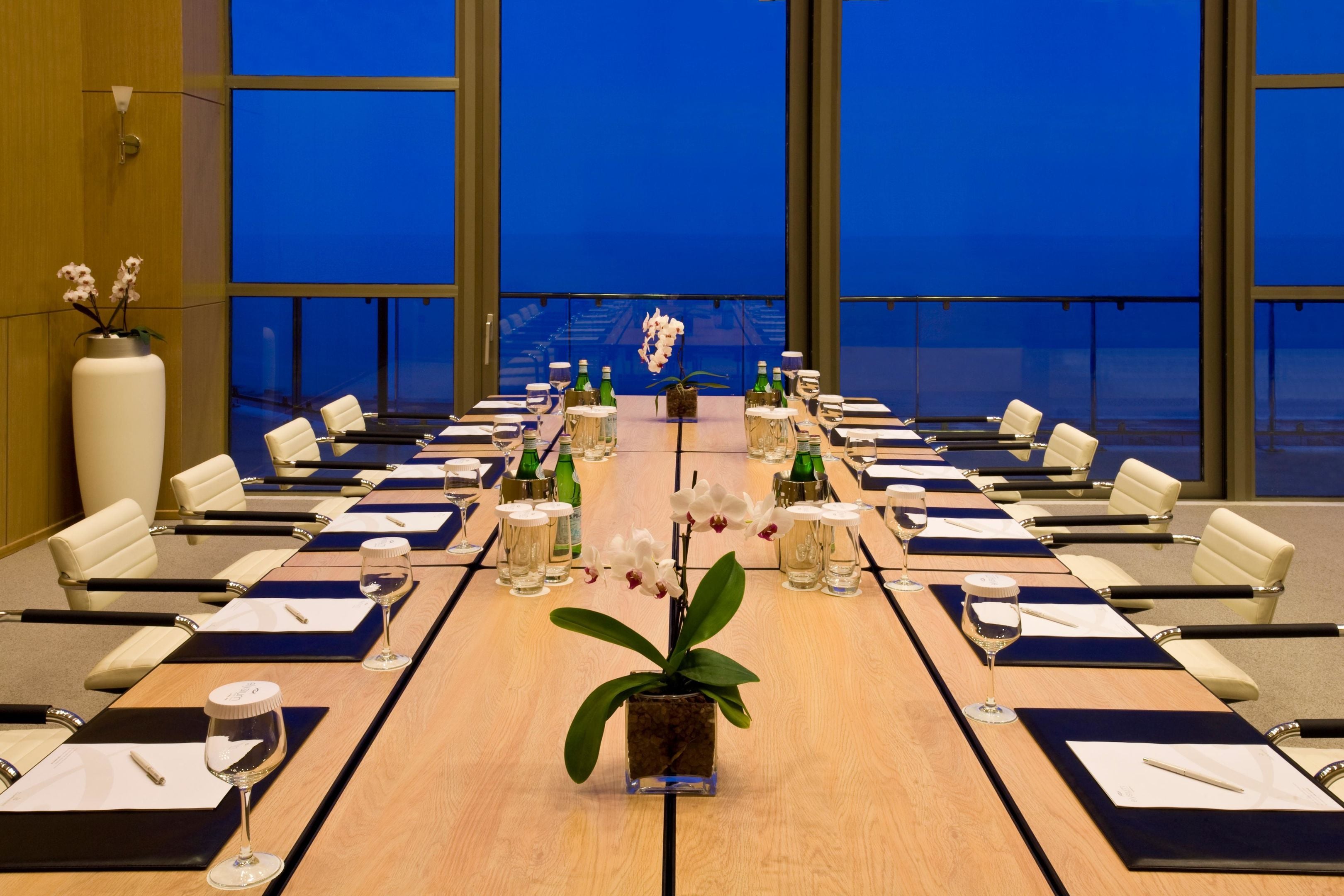 A conference room with a long table, chairs, and a potted plant.